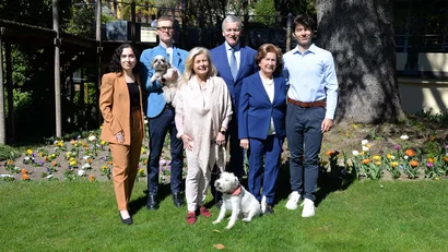 Sechs Personen und zwei Hunde posieren im Garten bei sonnigem Wetter