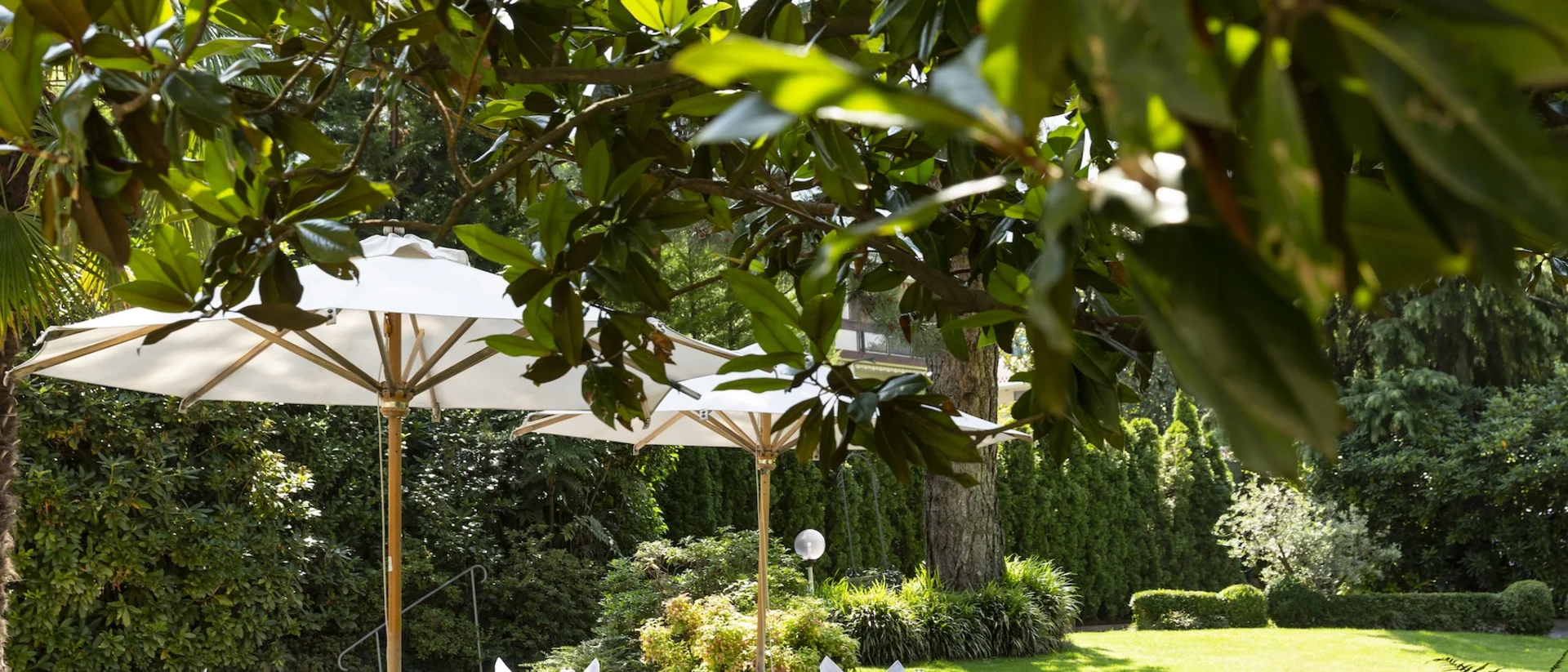 Outdoor terrace with set tables and umbrellas in a green garden