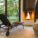 Relax room with fireplace, loungers, and view of green garden