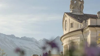 Historisches Gebäude mit Statuen vor verschneiten Alpenbergen