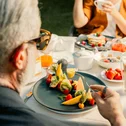 Person eating fruit salad at an outdoor breakfast table