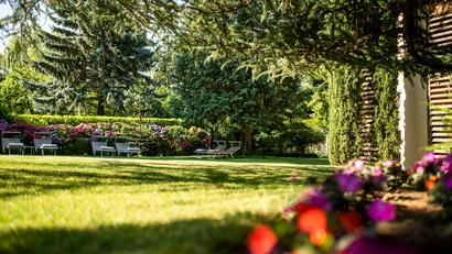 Sonniger Garten mit Liegestühlen, Bäumen und bunten Blumen