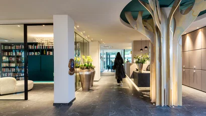 Moderner Hotellobbyflur mit Baumskulptur und Person im Hintergrund