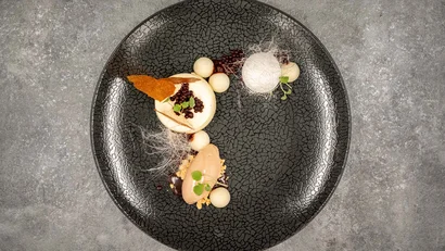 Elegantes Dessert mit Creme, Schokolade und Dekoration auf schwarzem Teller