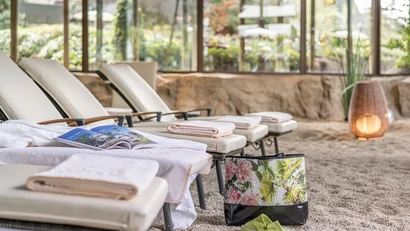 Liegestühle mit Handtüchern in einem entspannten Ruheraum mit Steinteppich
