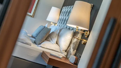 Blick auf ein gemütlich hergerichtetes Schlafzimmer mit Nachttisch und Lampe