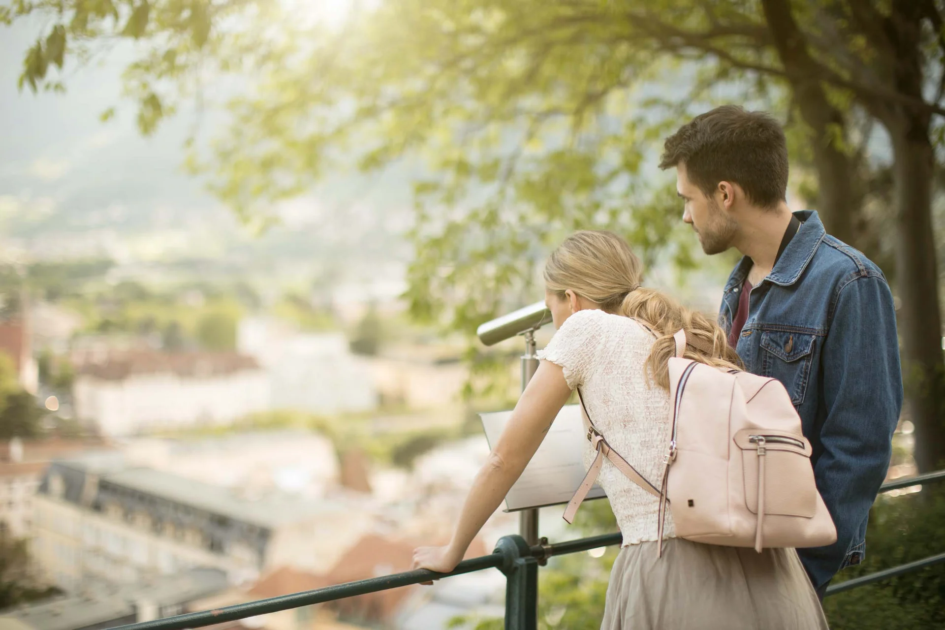 Young couple looking at city view through a binocular outdoors