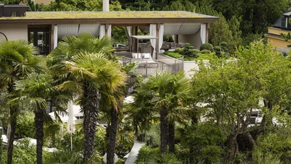 Moderner Pavillon mit weißer Outdoor-Möblierung in einem üppigen Garten mit Palmen