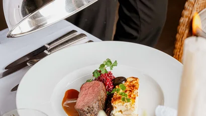 Gedeckter Tisch mit einem servierten Gourmetgericht und einer Servierhaube