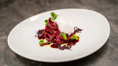 Rote Pasta mit Schaum und grüner Dekoration auf weißem Teller