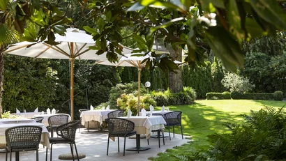 Restaurantterrasse im Garten mit Tischen, Stühlen und Sonnenschirmen