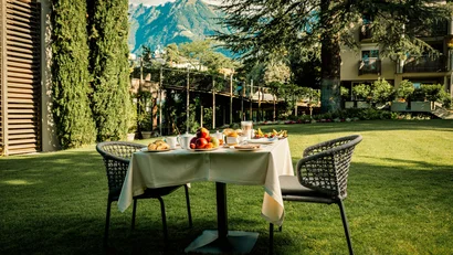 Gedeckter Frühstückstisch im Garten mit Bergblick